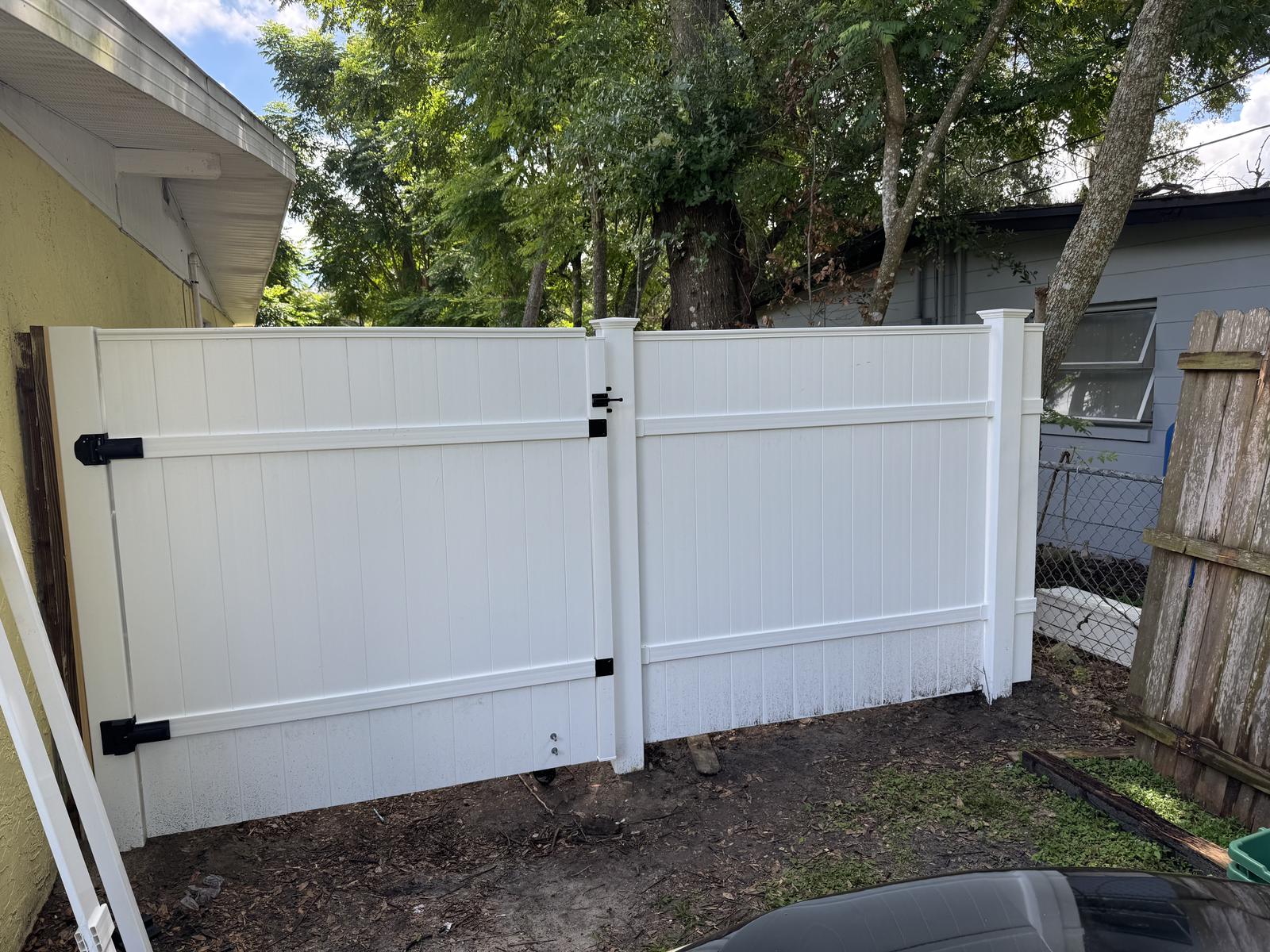 Completed white vinyl privacy fence with gate